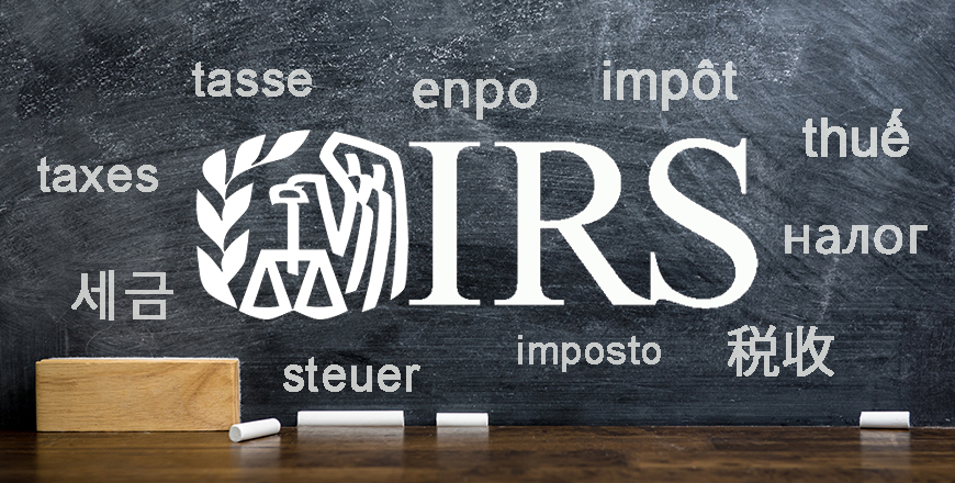 Multilingual words shown in different languages written on a black chalkboard, with with a desk and IRS logo.